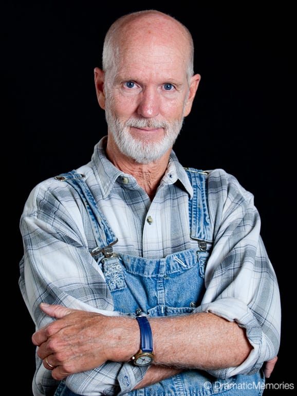 happy farmer standing in overalls and a plaid shirt